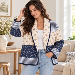 K&ouml;nnte beinhalten: Eine gesteppte Jacke im Patchwork-Design mit cremefarbenen, marineblauen und wei&szlig;en Blumenmustern sowie marineblau-wei&szlig;em Vichy-Karo. Die Jacke hat lange &Auml;rmel, einen Schalkragen und einen geraden Saum und wird &uuml;ber einem wei&szlig;en Oberteil getragen.