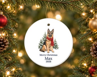 May include: A round white ceramic ornament featuring a German Shepherd dog wearing a red scarf, sitting in front of two green pine trees. Below the dog, the text reads Merry Christmas, Max, and 2026 in a dark blue serif font.