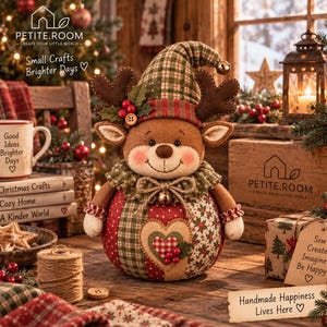 May include: A plush reindeer doll featuring a round body with red and green patchwork fabric, a heart applique, and a matching pointed hat. The reindeer has brown felt antlers, a ruffled collar with a small bell, and a smiling embroidered face.