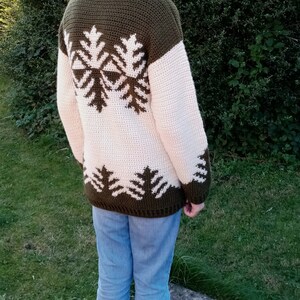 May include: A green and cream crocheted sweater with a snowflake design on the back.
