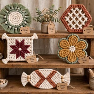 May include: A collection of five macrame coasters in various shapes and colors, including a round sage green and cream piece, a hexagonal terracotta and cream design, a square cream and maroon star pattern, a flower-shaped mustard and green coaster, and an oval terracotta and cream candy-shaped coaster, each with a small tag.