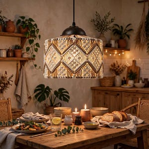May include: A cylindrical pendant light fixture featuring an intricate macrame shade with a geometric diamond pattern in cream and brown cord, suspended from a black metal canopy by a single cord, emitting a warm glow from the interior light.