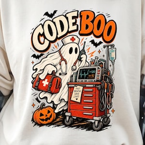 Puede incluir: Una sudadera color crema con un gráfico de un fantasma vestido de enfermero con estetoscopio, sosteniendo un maletín médico. El texto dice CODE BOO y FAST BREATHE SAVE LIVES. Incluye una calabaza, murciélagos y un carrito médico rojo.
