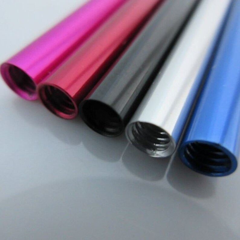 May include: Five metal tubes in different colors: pink, red, black, silver, and blue. The tubes are all the same size and have a threaded end.