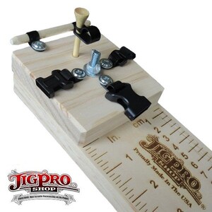 Puede incluir: Un jig de madera con abrazaderas negras y una regla marcada en pulgadas y cent&iacute;metros. El jig se utiliza para proyectos de carpinter&iacute;a y tiene un tee de golf en el centro. El texto "JigPro Shop" est&aacute; impreso en el jig. Fabricado con orgullo en los Estados Unidos.