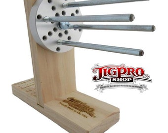 May include: A wooden jig with a metal base and multiple metal rods extending out. The jig is labeled "JigPro Shop" and "Proudly Made in the USA".