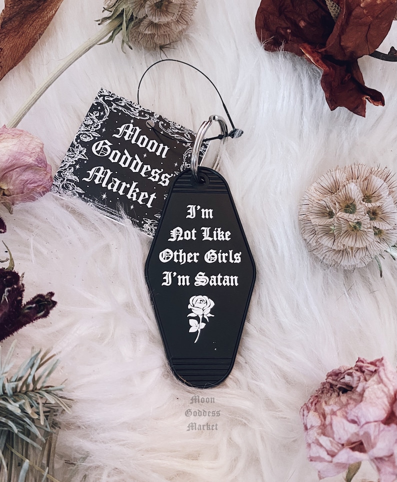May include: Black motel key chain with a white rose and the text "I'm Not Like Other Girls I'm Satan".