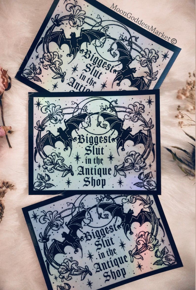 May include: Three rectangular stickers with a black border and a design featuring bats, flowers, and the text "Biggest Slut in the Antique Shop." The stickers have a holographic, iridescent finish.