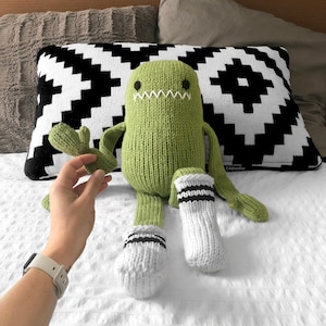 May include: A green knitted monster toy with white and black striped socks. The monster has a stitched-on mouth and eyes.
