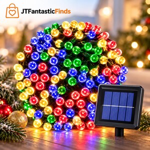 May include: A dense coil of multi-colored LED string lights featuring red, blue, green, and yellow bulbs. A black square solar panel with a grid pattern is connected to the light strand, positioned to the right of the coiled lights.