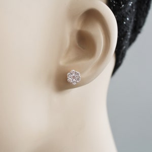 May include: A pair of silver flower-shaped stud earrings with clear cubic zirconia stones.