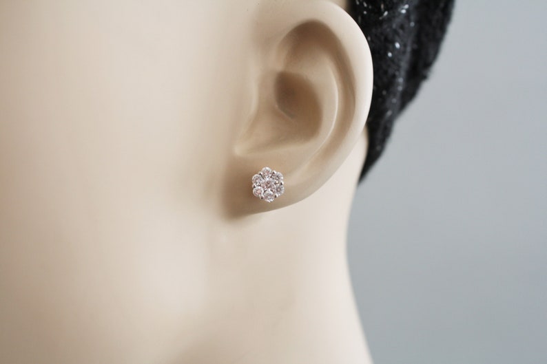 May include: A pair of silver flower-shaped stud earrings with clear cubic zirconia stones.