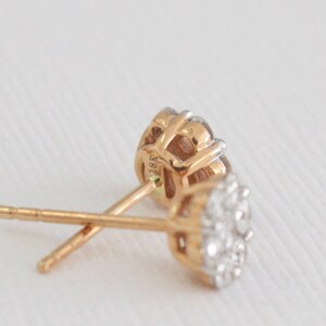 May include: A pair of gold earrings with a cluster of small diamonds. The earrings are marked "18K" on the back.