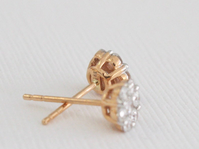 May include: A pair of gold earrings with a cluster of small diamonds. The earrings are marked "18K" on the back.