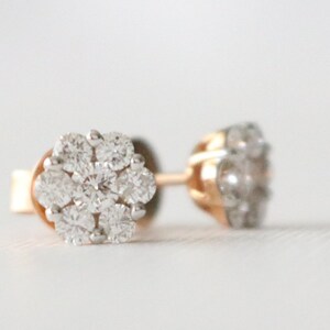 May include: A pair of gold stud earrings with a cluster of small, clear diamonds in a flower shape.