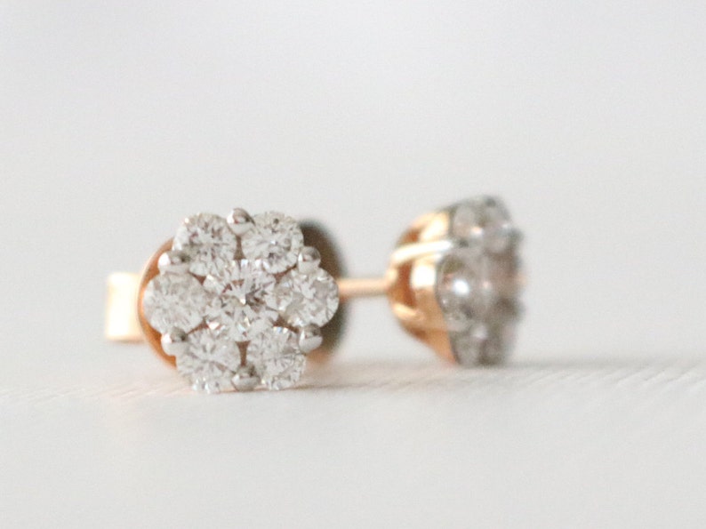 May include: A pair of gold stud earrings with a cluster of small, clear diamonds in a flower shape.