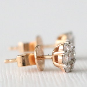 May include: A pair of gold stud earrings with a cluster of small diamonds in the center.