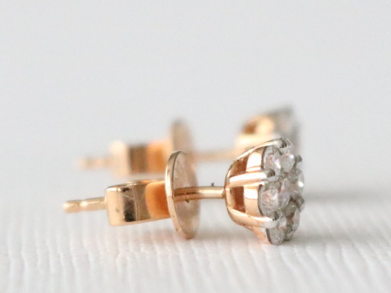 May include: A pair of gold stud earrings with a cluster of small diamonds in the center.