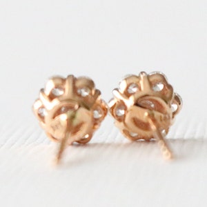 May include: A pair of rose gold stud earrings with a cluster of small clear stones.