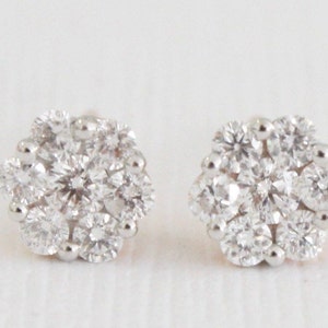 May include: A pair of silver stud earrings with a cluster of small, round, clear diamonds set in a flower shape.