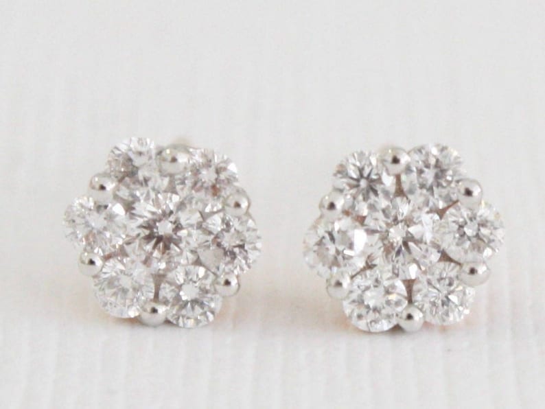 May include: A pair of silver stud earrings with a cluster of small, round, clear diamonds set in a flower shape.