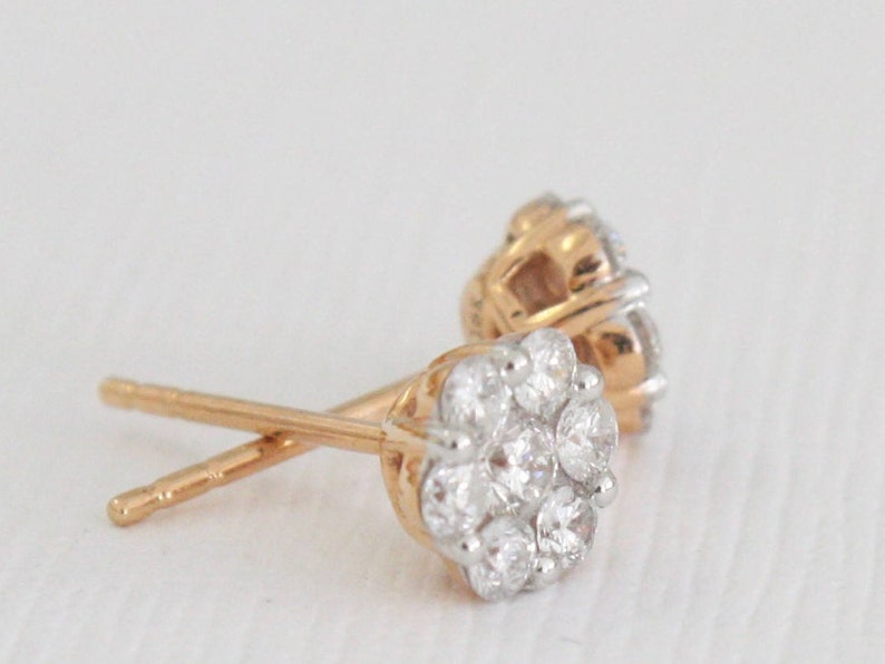 May include: A pair of gold stud earrings with a cluster of small, clear diamonds in a flower shape.