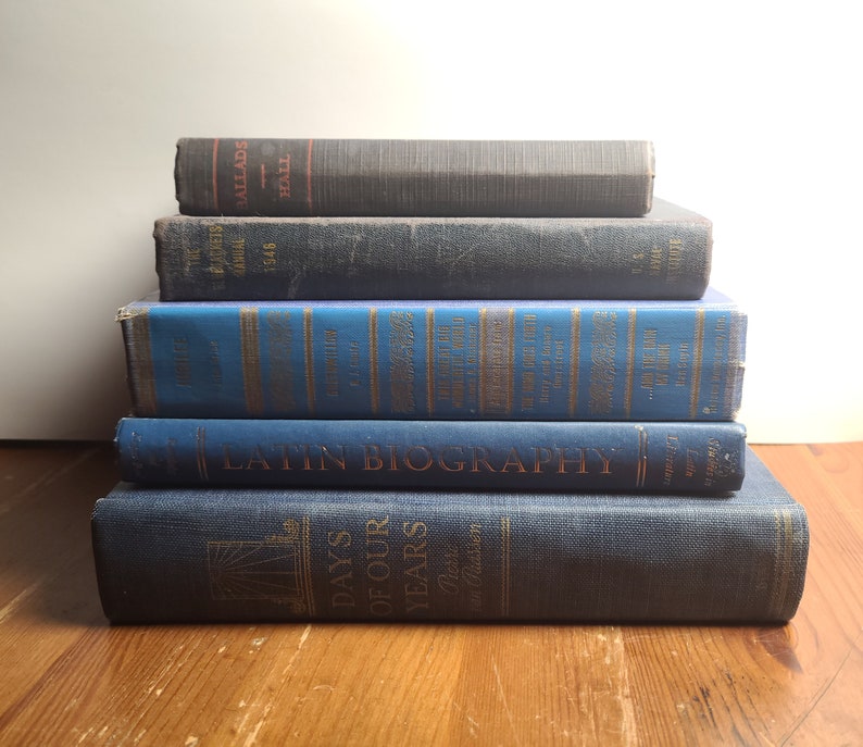 May include: A stack of five blue hardcover books with gold lettering. The top book has the title "Latin Biography" and the bottom book has the title "Days of Our Years".