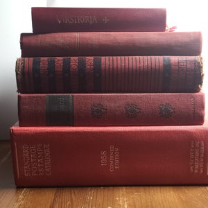May include: A stack of six red hardcover books. The top book has the text "VIRSIKIRJA +" on the spine. The bottom book has the text "STANDARD POSTAGE STAMPS CATALOGUE 1958 COMBINED EDITION SCOTT PUBLICATIONS INC NEW YORK" on the spine.
