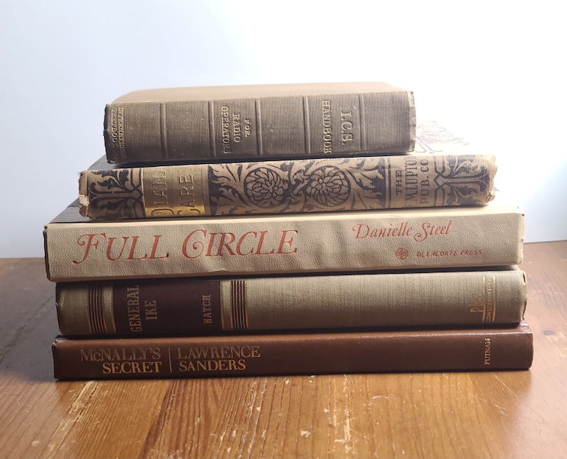 May include: A stack of six vintage hardcover books with brown and beige covers. The titles include "Full Circle" by Danielle Steel, "General Ike" by Hatch, "McNally's Secret" by Lawrence Sanders, "The Mlupto Pub. Co.", "For Radio Operators" and "I.C.S. Handbook".