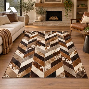 May include: A rectangular area rug featuring a chevron pattern composed of stitched cowhide panels in various shades of brown, black, white, and gray, with some panels displaying natural spotted and mottled animal hide textures.