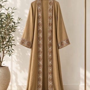 May include: A floor-length tan open-front robe featuring long, wide sleeves and a vertical panel of intricate floral embroidery in shades of brown, orange, and cream along the front opening and the cuffs of the sleeves.