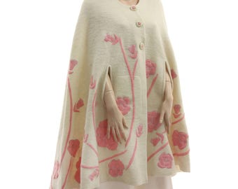 May include: A cream-colored wool cape with pink floral embroidery. The cape has a button closure and side slits.