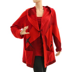Könnte beinhalten: Ein roter Kapuzen-Cardigan mit Patchwork-Design. Die offene Jacke hat zwei Taschen und schwarze Akzente. Die Ärmel haben eine gerollte Manschette. Der Cardigan wird auf einer Schaufenquin präsentiert.