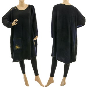 Könnte beinhalten: Ein schwarzes Tunika-Kleid mit langen Ärmeln, rundem Ausschnitt und lockerer Passform. Das Kleid hat eine große Tasche mit blauem und goldenem Design. Das Kleid wird mit schwarzen Leggings getragen. Das Kleid hat ein einzigartiges, künstlerisches Design.