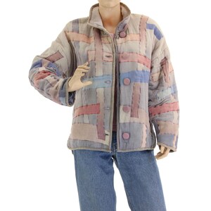 Könnte beinhalten: Eine gesteppte Jacke mit Patchwork-Muster in Rosa-, Blau- und Grautönen. Die Jacke hat einen Knopfverschluss und einen Stehkragen.