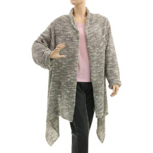 May include: A long, open-front cardigan in a speckled gray and cream knit fabric. The cardigan has a shawl collar and long sleeves. The mannequin is also wearing a pink t-shirt and black pants.
