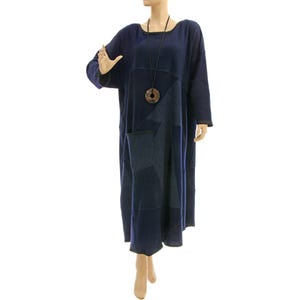 Könnte beinhalten: Ein langes, marineblaues Patchworkkleid mit einer runden, braunen Anhänger-Halskette. Das Kleid hat eine lockere Passform und einen leicht ausgestellten Rock.