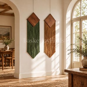 May include: Two wall hangings featuring diamond-shaped dark wood tops with long, straight fiber fringe. One hanging has deep green fringe, and the other has warm brown fringe. The text BasketJoyFinds is centered between the two pieces.