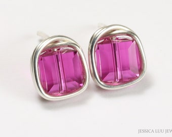 Puede incluir: Un par de pendientes de botón con cristales rectangulares de color magenta engastados en un marco de alambre plateado. Los pendientes se muestran sobre un fondo blanco, resaltando el diseño y el color de la joyería.