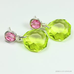 Puede incluir: Un par de pendientes colgantes con una cuenta rosa y un gran cristal verde lima facetado. Los pendientes tienen postes y alambres de conexión plateados. La joya está sobre un fondo blanco.