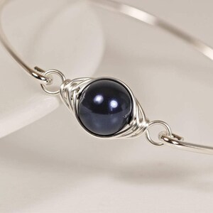May include: A silver wire wrapped bracelet with a single black pearl bead.
