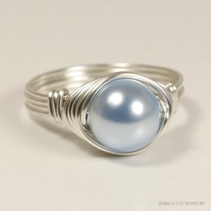 May include: A silver wire wrapped ring with a light blue pearl in the center.