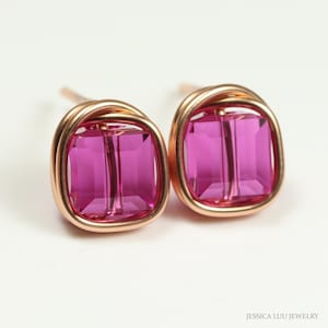 May include: A pair of pink square-shaped earrings with a rose gold wire frame. The earrings are made with a single pink crystal in each frame.