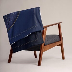 Printful mockup of the star map throw blanket draped over a wooden armchair. Props not included.