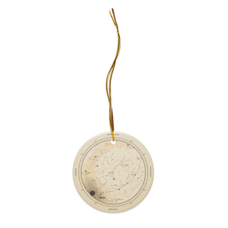 The flat round ceramic star map ornament with its gold cord, shown small.