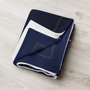 Printful mockup of the throw blanket folded, showing the soft white back.