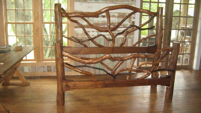 May include: A rustic wooden bed frame with a headboard and footboard made from natural branches. The frame is stained a dark brown colour and has a natural, organic look.