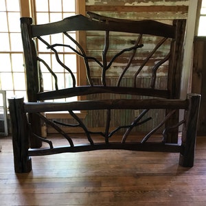 May include: A rustic wooden bed frame with a headboard and footboard made of thick branches. The frame is dark brown and has a natural, weathered look. The branches are arranged in a criss-cross pattern, creating a unique and eye-catching design.