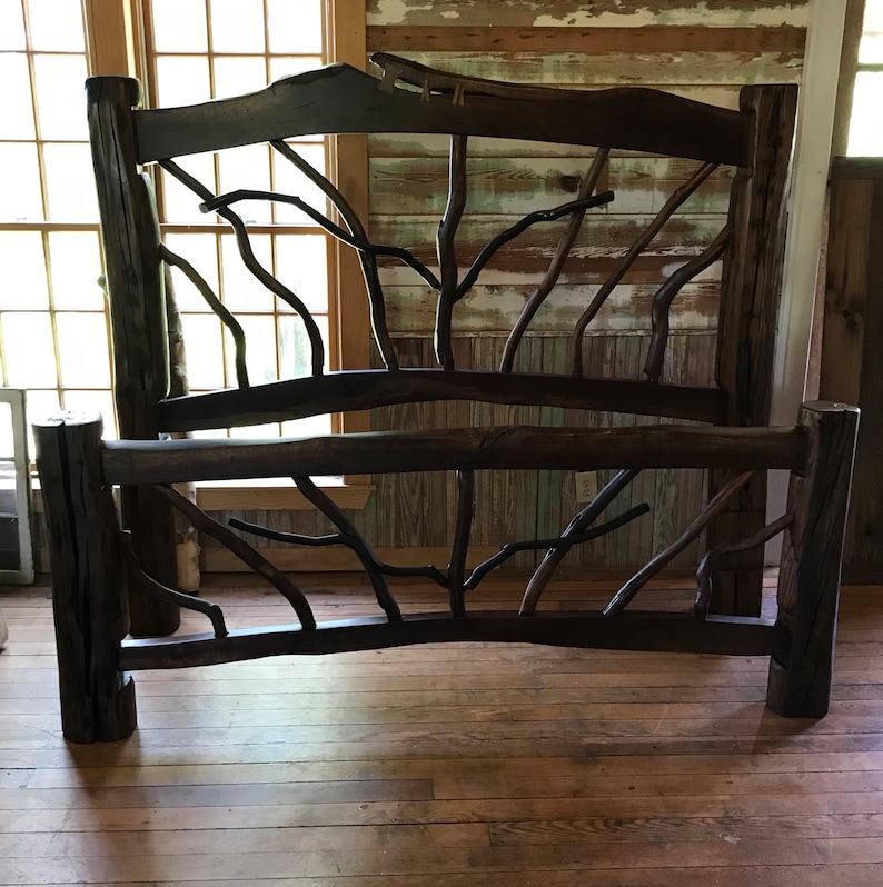 May include: A rustic wooden bed frame with a headboard and footboard made of thick branches. The frame is dark brown and has a natural, weathered look. The branches are arranged in a criss-cross pattern, creating a unique and eye-catching design.