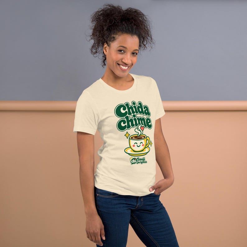 The same woman posing at an angle in the Heather Natural Chida chime coffee t-shirt, showing the front print and the small QR code print on the sleeve.